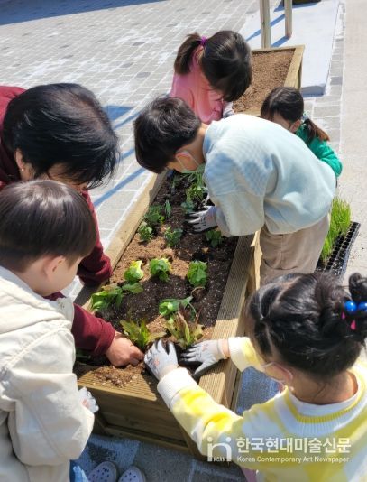 어린이들이 원목 상자텃밭에 모종을 심고 있는 모습.