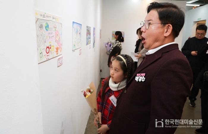 박강수 마포구청장이 수상 어린이와 함께 전시된 그림을 살펴보고 있다.