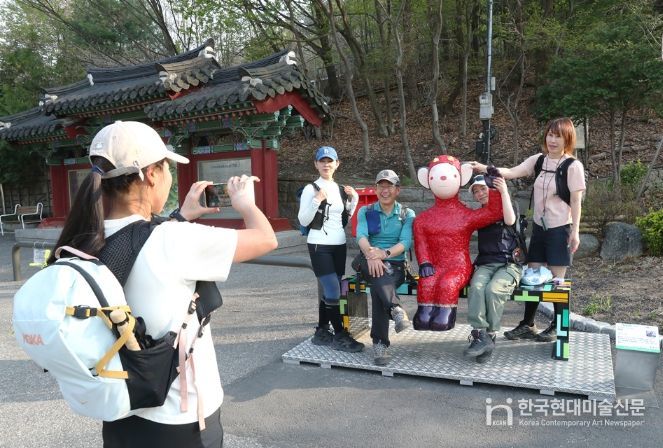 관악산 등산로 입구 으뜸공원에 설치된 작품 ‘하이’와 함께 기념사진을 촬영하는 등산객들